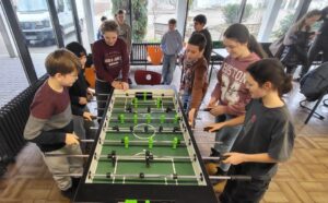 Schüler im Aufenthaltsraum spielen am neuen Tischkicker