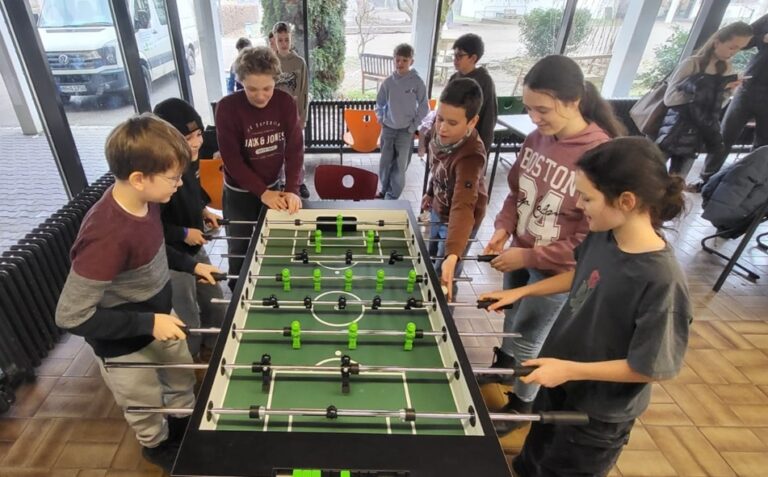 Schüler im Aufenthaltsraum spielen am neuen Tischkicker